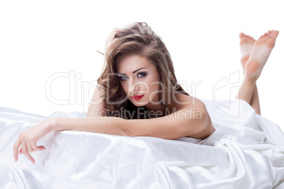 Beautiful nude model lying on silk sheets