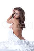 Sensual woman posing naked, hiding behind sheet