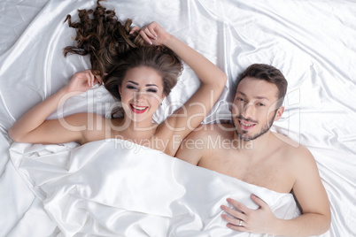 Cheerful heterosexual couple posing in bed
