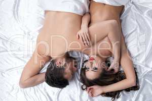 Satisfied sexual partners posing in bed