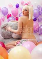 Playful topless blonde posing with balloons