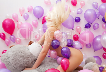 Nude blonde posing with balloons and teddy bear
