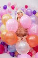 Sensual young blonde posing nude among balloons