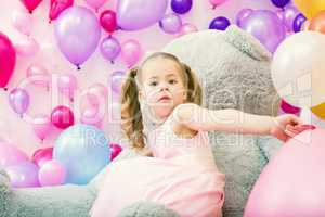 Surprised girl posing at camera with balloons