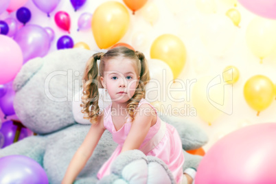 Funny little girl playing in studio with balloons