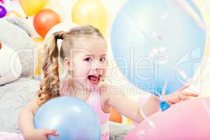 Cheerful little girl posing with blue balloons