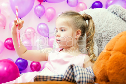 Funny little girl attentively looks on lollipop