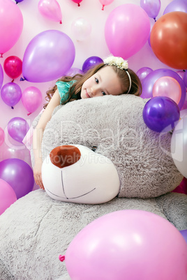 Cute curly girl posing lying on big plush bear