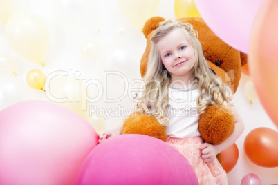 Smiling blonde girl playing with teddy bear