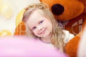 Smiling blue-eyed girl posing with teddy bear