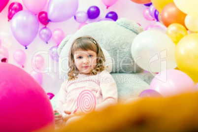 Cute girl posing in playroom on balloons backdrop