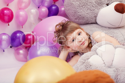 Funny little girl posing lying on big plush bear