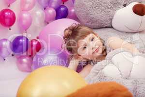 Funny little girl posing lying on big plush bear