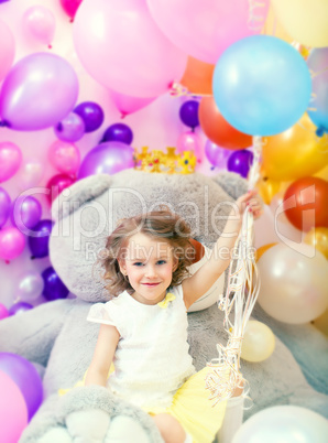 Cheerful girl posing holding bunch of balloons