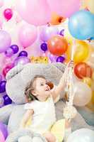 Cheerful little girl grabs bunch of balloons