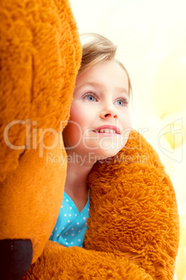 Cute little girl in arms of teddy bear, close-up