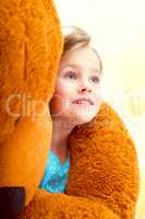 Cute little girl in arms of teddy bear, close-up