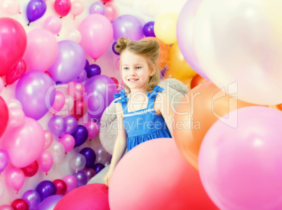 Adorable girl posing among colorful balloons