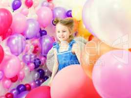 Adorable girl posing among colorful balloons