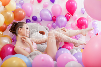 Pretty model posing with balloons and teddy bear
