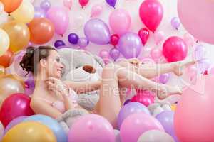 Pretty model posing with balloons and teddy bear