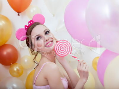 Image of smiling comely girl posing with lollipop