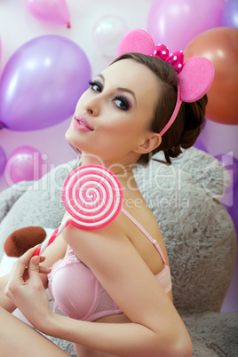 Cute young woman posing with pink lollipop