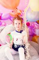 Funny girl holding lollipops and bunch of balloons