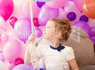Sympathetic little girl holding bunch of balloons