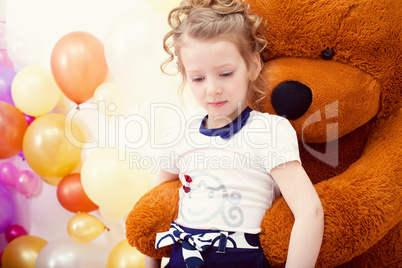 Cute girl posing in embrace with big teddy bear