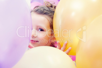 Cute little girl peeking out from behind balloons