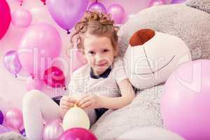 Smiling girl sits leaning on big teddy bear