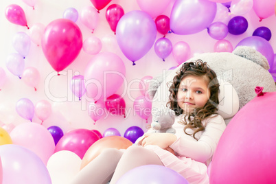 Playful little girl posing in studio with balloons
