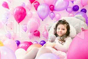 Playful little girl posing in studio with balloons