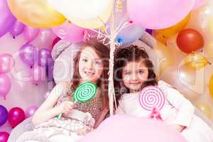 Beautiful sisters with lollipops posing at camera