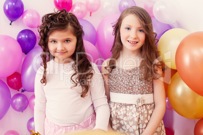 Two merry girlfriends posing on balloons backdrop