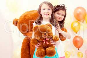 Pretty sisters posing with teddy bears in playroom