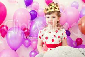 Cute girl posing in crown on balloons background