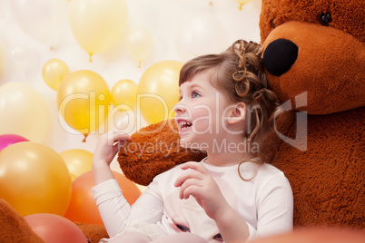 Joyful little girl posing hugging plush bear