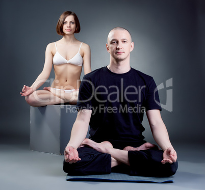 Shot of meditating yoga trainers, on gray backdrop