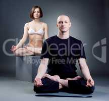 Shot of meditating yoga trainers, on gray backdrop