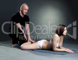 Senior yoga trainer helping girl exercising