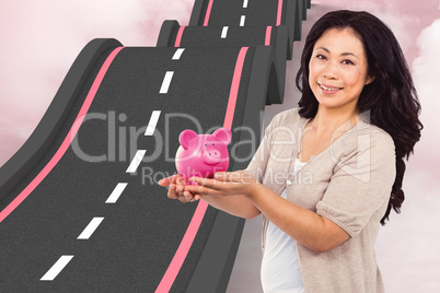 Composite image of happy woman holding a piggy bank