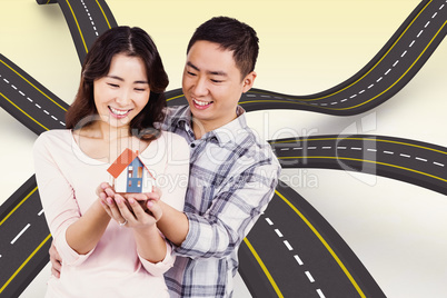 Composite image of happy couple holding a model house