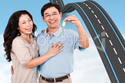 Composite image of smiling couple holding a set of keys