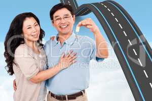 Composite image of smiling couple holding a set of keys