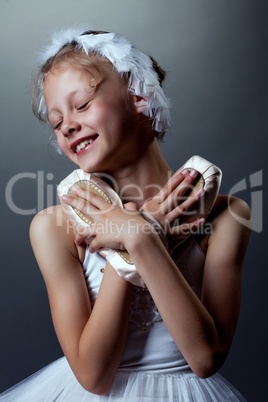 Portrait of happy little ballerina cuddles pointes