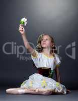 Emotional ballet dancer posing looking at flower