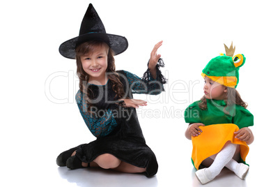 Cute sisters posing in costumes of witch and frog