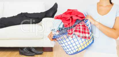 Composite image of brunette holding a basket full of laundry